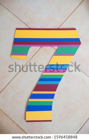 Decorations for the child's birthday. Handmade multicolor number seven for birthday party from paper. DIY.