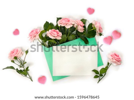 Decoration of Valentine Day. Beautiful flowers pink roses in postal envelope, pink hearts and blank sheet with space for text on a white background. Top view, flat lay