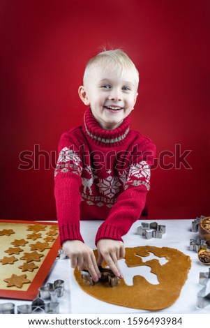A child cuts a gingerbread cookie with a cookie cutter a snowflakes on a white background. Little cute mom's assistant.