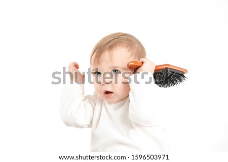 Stock studio photo with a white background of a baby with a comb in his hand