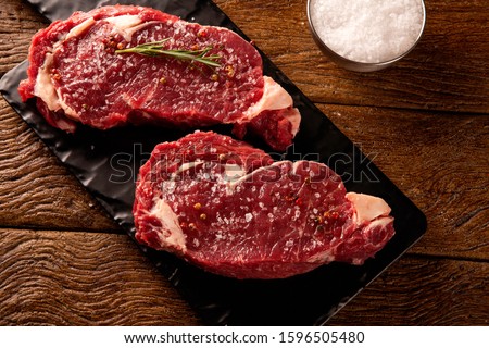 Raw ancho meat  for cooking on dark cutting board. Wooden background.