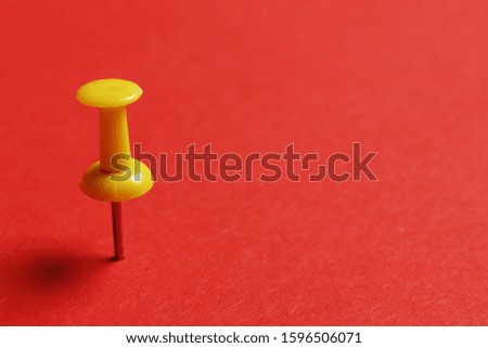 Yellow pin on red paper.