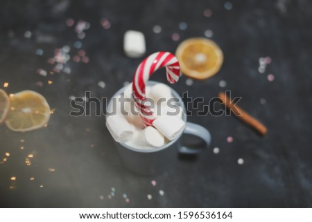 Cup with marshmallows, candy cane, tangerines. Winter decor for holidays. New Year still life. Christmas tree background. Christmas, winter, New year concept. Flat lay, top view, copy space