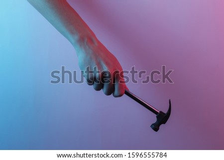 Hand holds a hammer. Creative pop art pink blue neon color. Trendy gradient illumination. Night light