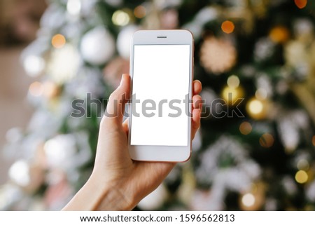 Mobile phone and Christmas tree decoration in classic and luxury colors with pink and gold balls. Happy New Year and Xmas theme side view