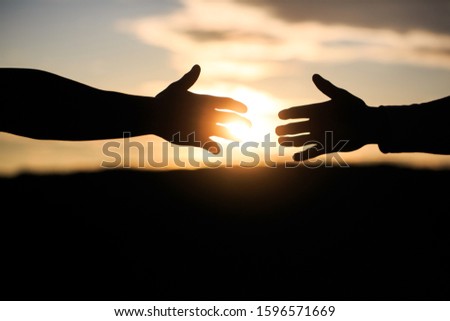 Friendly handshake, friends greeting, teamwork, friendship. The outstretched hands, salvation, help silhouette, concept of help. Giving a helping hand. Rescue, helping gesture or hands.