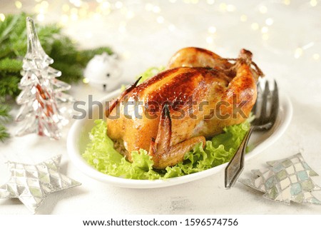 Roasted whole chicken on lettuce leaves. Christmas light background.