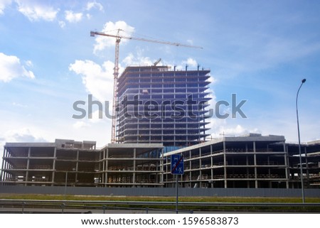 Concrete skyscrapers. Construction of new residential buildings. New Apartments for settlement. Crane builds a house on a background of blue sky. Urbanization. 