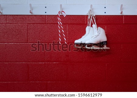Christmas background of figure skates with candy cane hanging over red wall with copy space 