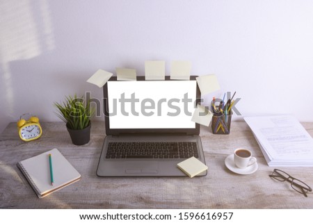 Modern white office desk table mockup ,work space with laptop computer with white screen for you text or 
image,green grass,cup of coffee and a stack of papers on white rock background.