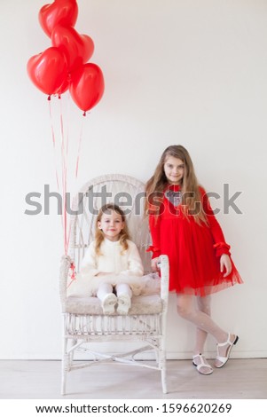Children with red heart-shaped balloons at the holiday