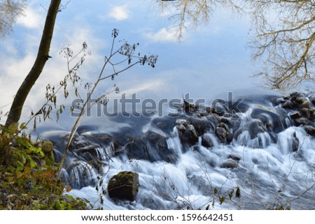 Stone cascades in the river and reflection of trees on the water