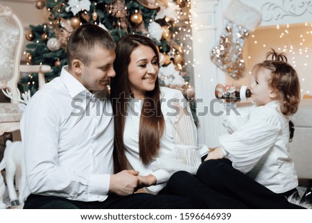 Happy family of mother, father and little daughter hugging and celebrating new year in front of Christmas tree in decorated interior. Celebrating Christmas.  Family. Happiness.