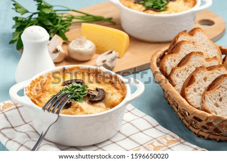 Casserole with chicken, mushrooms and cheese, known in Russia as julienne in white bowl with herbs