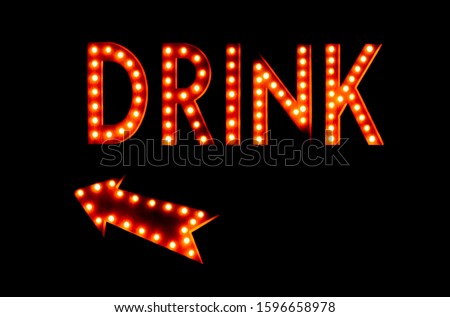 Illuminated vintage neon marquee drink sign with arrow against a black background at night. Drinks this way sign.
