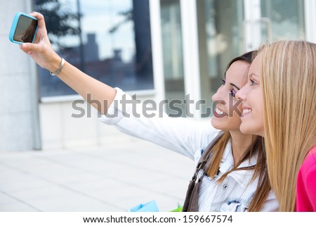 Outdoor portrait of two friends taking photos with a smartphone