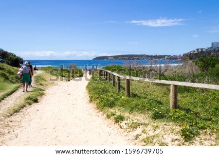 People walking to and from Freshwater beach on a sunny day, Sydney, Australia