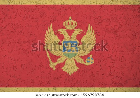 Montenegro flag depicted in bright paint colors on old relief plastering wall. Textured banner on rough background