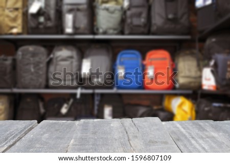 empty wooden table top on the background of modern photo bags and photo backpacks on the shelf in the store