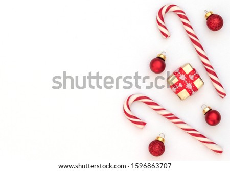 Christmas white background with two candy canes, wrapped gift box with red ribbon and red Xmas balls. New Year greeting card. Christmas, New Year concept. Flat lay style with copy space.