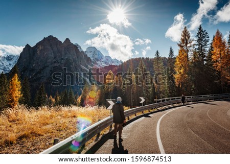 Young male photographer from behind taking pictures of dolomites in Italian alps /  Dolomite mountains in background during sunny day / High ISO image