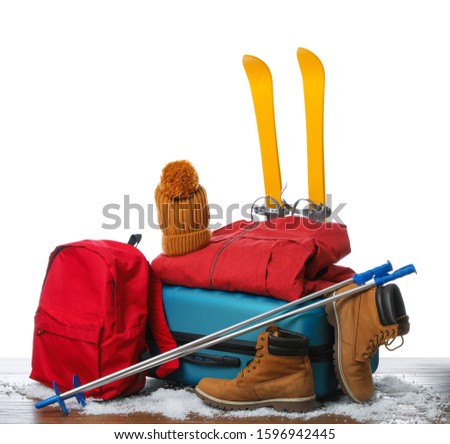 Suitcase with warm clothes and skis isolated on white. Winter vacation
