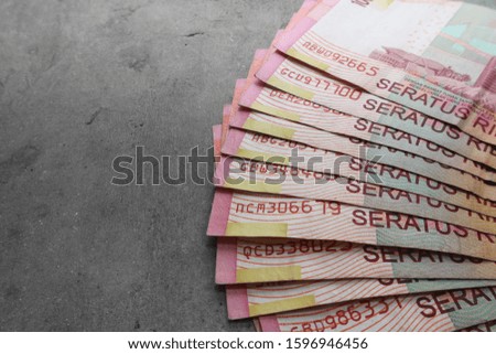 A lot of hundred thousandth Indonesian banknotes on a gray background with space on the left.