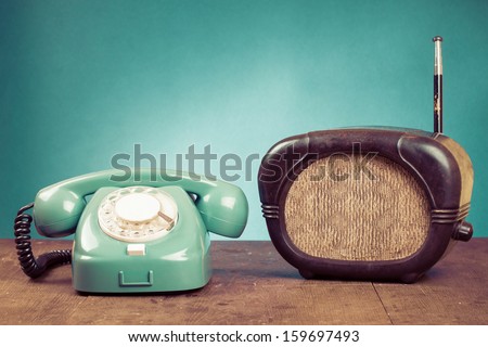 Retro rotary telephone and old radio on table in front mint green background
