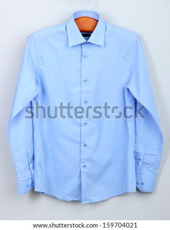 Male shirt on wooden hanger on wall background Royalty-Free Stock Photo #159704021
