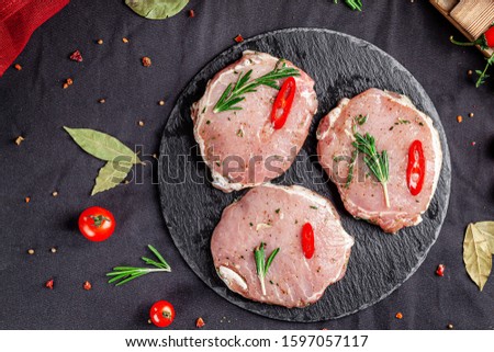 Semi-finished products. Marinated pork steak with rosemary and red chili for barbecue. Copy space, background image Royalty-Free Stock Photo #1597057117