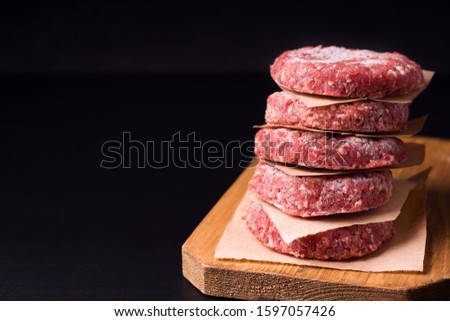 frozen raw minced meat in the form of cutlets on a black background. have copy space