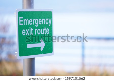 Emergency escape route green sign with direction arrow