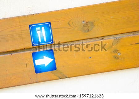 Stickers with fork and knife and arrow signs attached to lumber board on wall