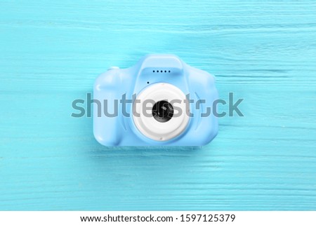 Toy camera on light blue wooden background, top view