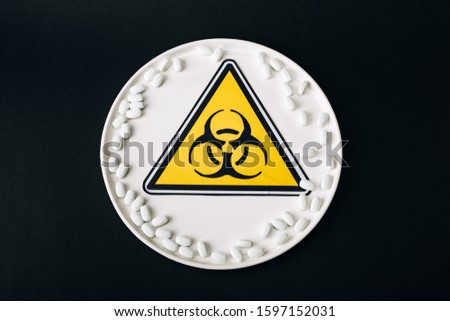 Top view of plate with pills and biohazard symbol isolated on black