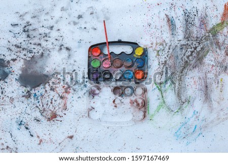 Various watercolor colors in a small tray with red,green,blue and many other colors placed on a white sheet of paper And there are many different colored patterns on the paper Used as an illustration