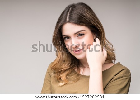 Closeup of pretty young woman smiling against gray background in studio