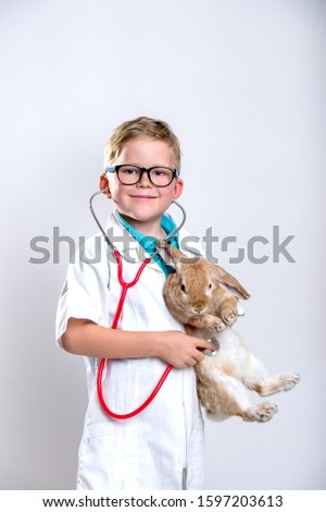 Portrait of child doctor in white medical uniform and glasses. School boy playing pediatrician.
