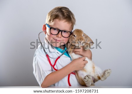 Portrait of funny child boy playing doctor with rabbit. Education for preschool and kindergarten. Pediatric, healthcare and people concept.