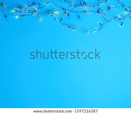 burning christmas garland on a white wire with colorful lights on a blue background, coy space