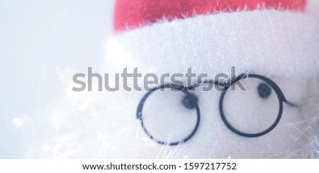 Soft toy abstract Santa Claus face with glasses and red hat, closeup eyes