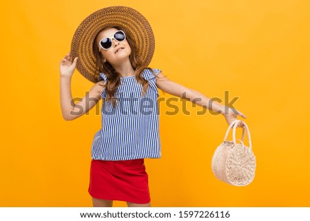 glamorous charming young child with a straw hat dancing on a yellow background