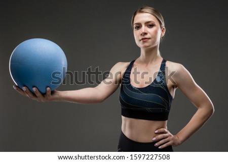 slim girl in sportswear holds a sports ball on a black background