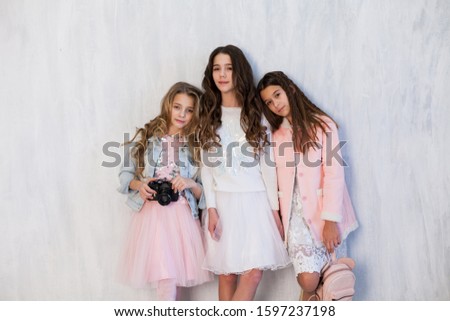 Portrait of three beautiful fashionable girl girlfriends in white pink clothes