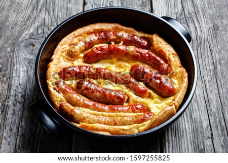 close-up of Toad in the hole, Sausage Toad, traditional English dish consisting of sausages in Yorkshire pudding batter in black ceramic baking dish