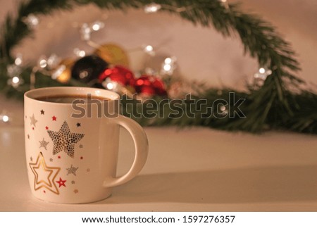 New year fist cup of coffee. stars patterned mug on the soft light with christmas objects and lights decor. 