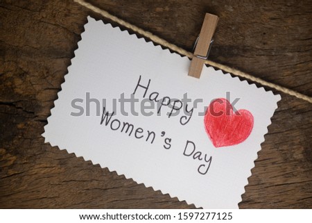 Happy Women's Day message on white paper with red heart on dark wooden background for International Women's Day, March 8.