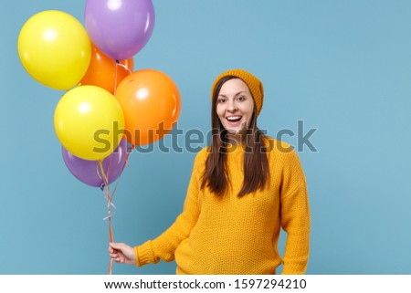 Excited young woman girl in sweater hat posing isolated on blue background studio portrait. Birthday holiday party, people emotions concept. Mock up copy space. Celebrating hold colorful air balloons