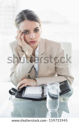 Attractive bored businesswoman looking at camera while sitting at her desk in the office