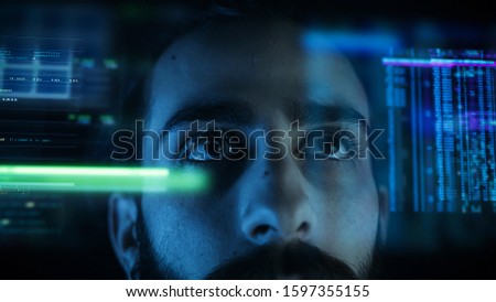 A close up of a young man eye controlling a futuristic computer system. Computer programmer coding on futuristic holographic display.